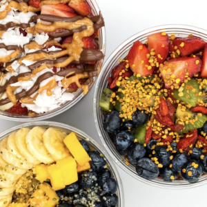 Three colorful Goodness Bowls topped with fresh fruits and superfoods.